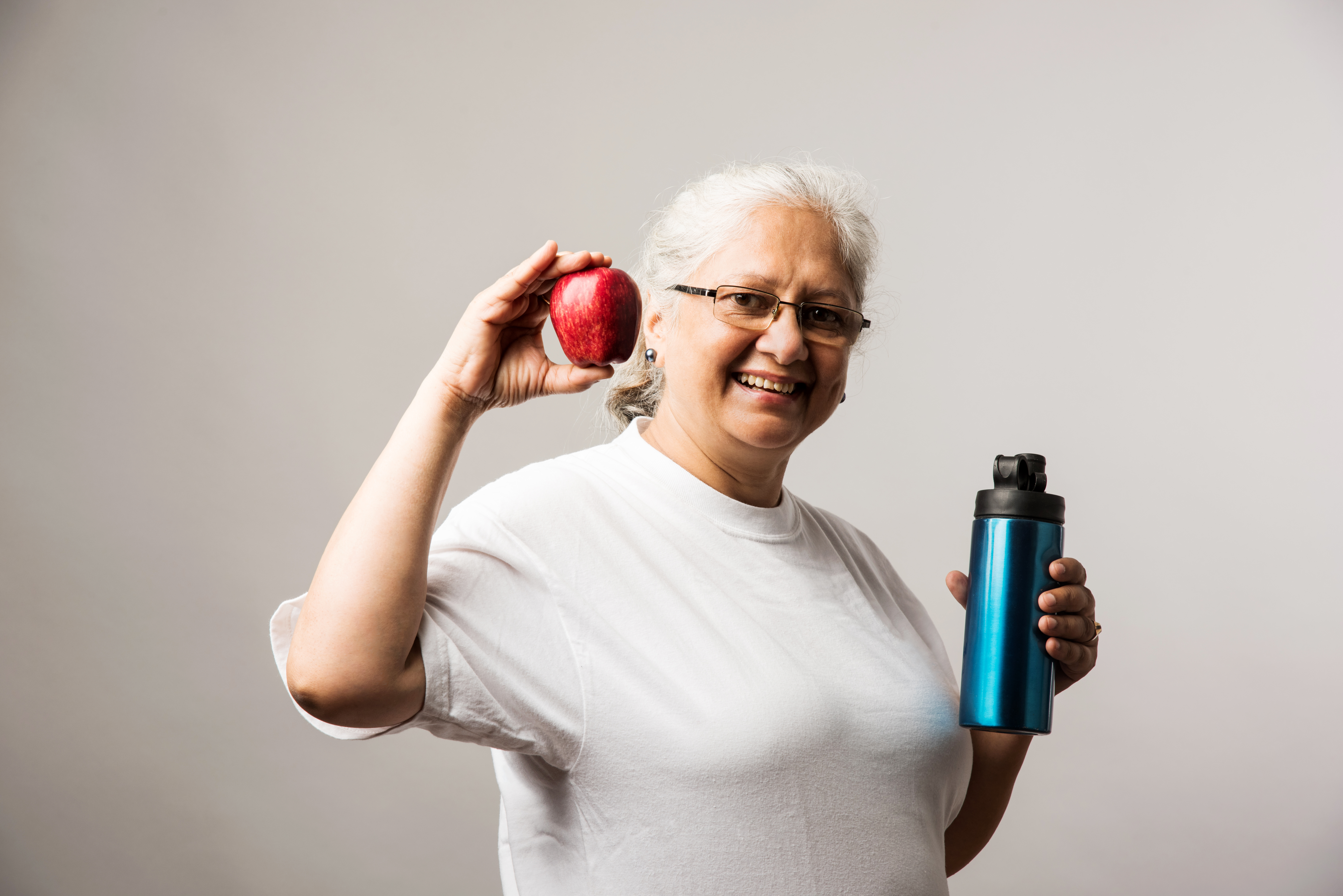 Senior woman holding apple and bottle