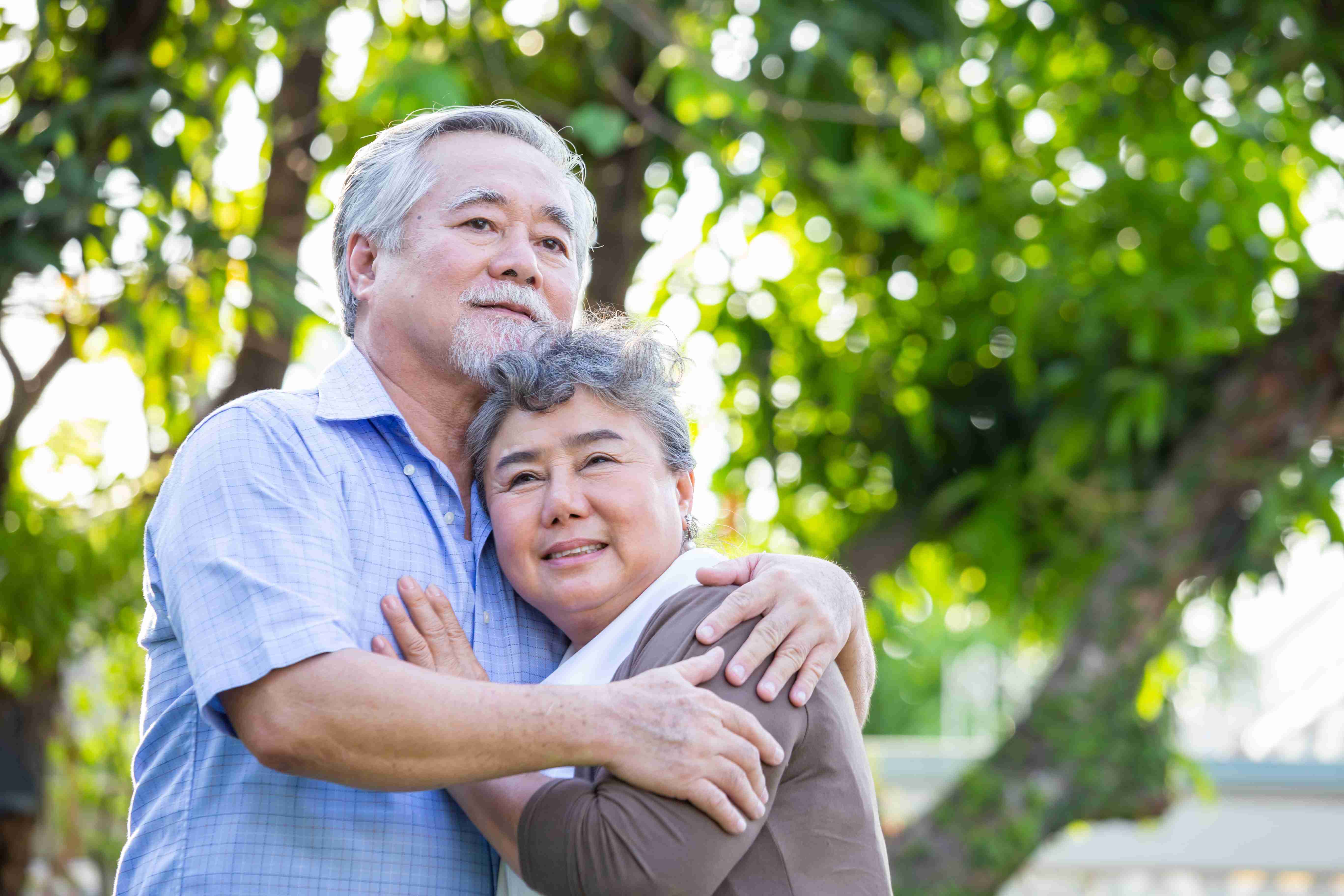 Elderly man embracing wife in the outdoors