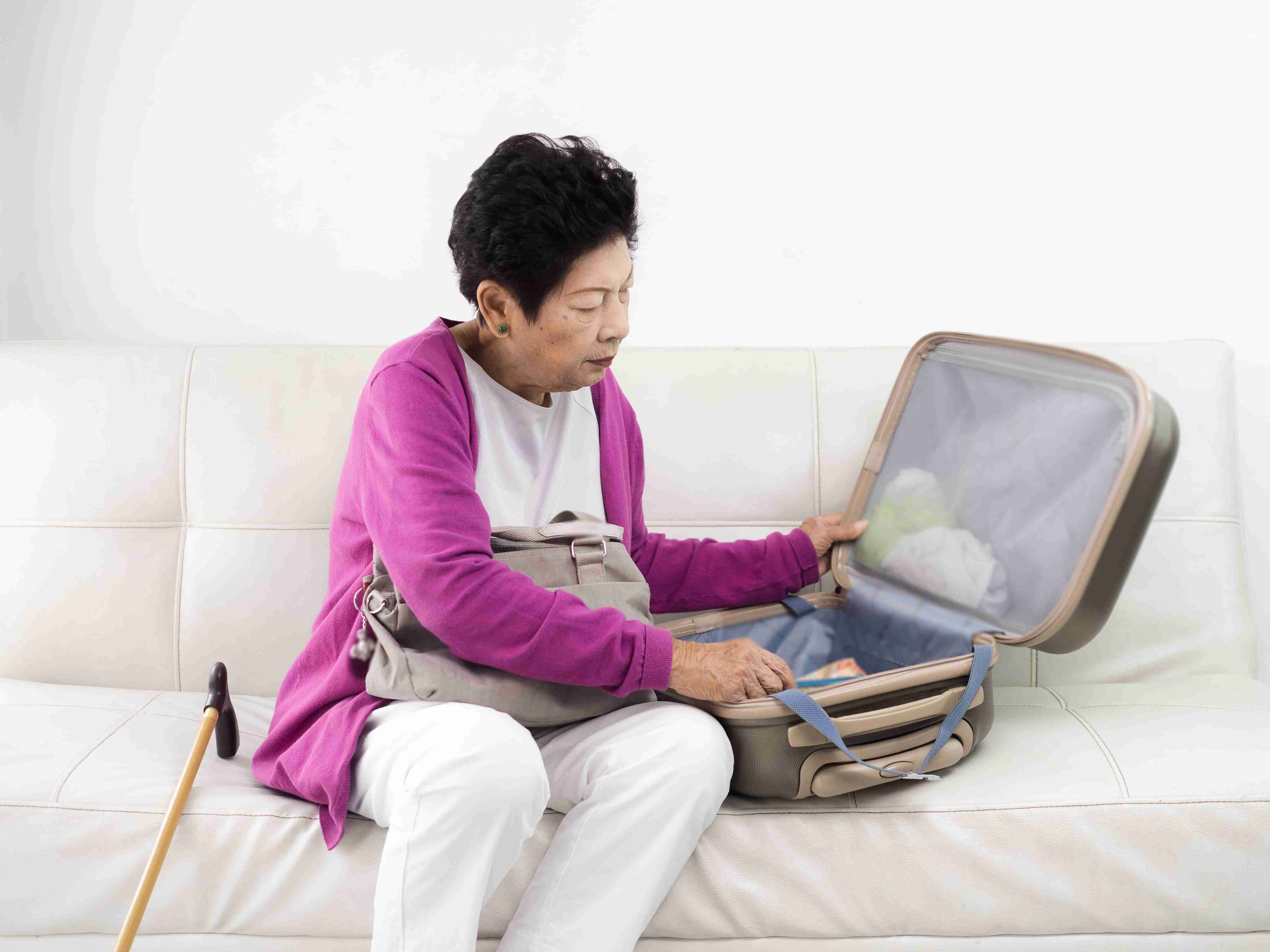 Elderly woman packing luggage to travel with dialysis