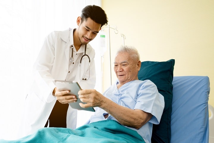 Elderly man and healthcare professional looking at a tablet before dialysis