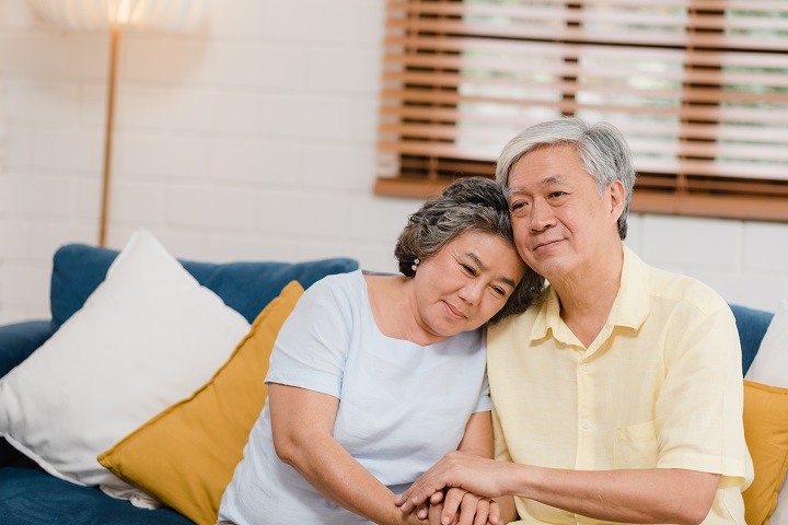 Elderly couple comforting each other while sitting on sofa