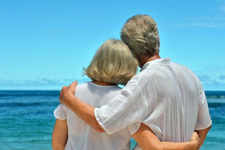 Elderly couple embracing each other while looking at the ocean