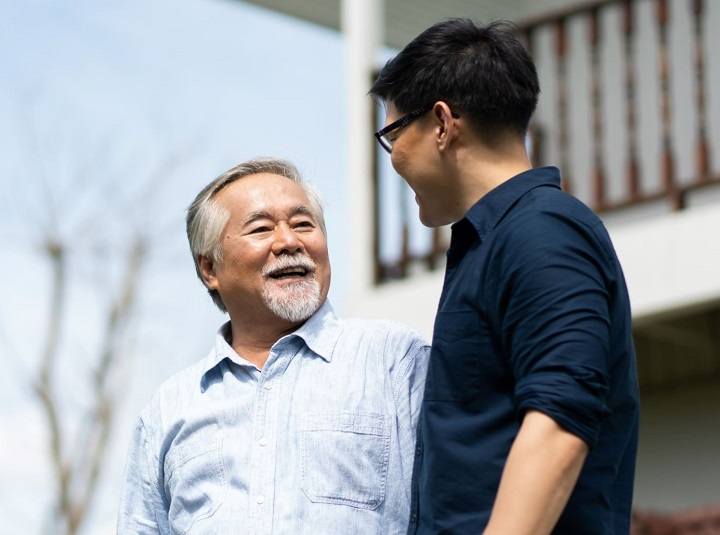 Elderly man chatting with young man outdoors