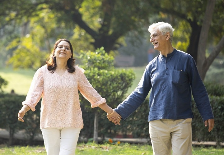 Indian elderly couple happily strolling in the park while holding hand