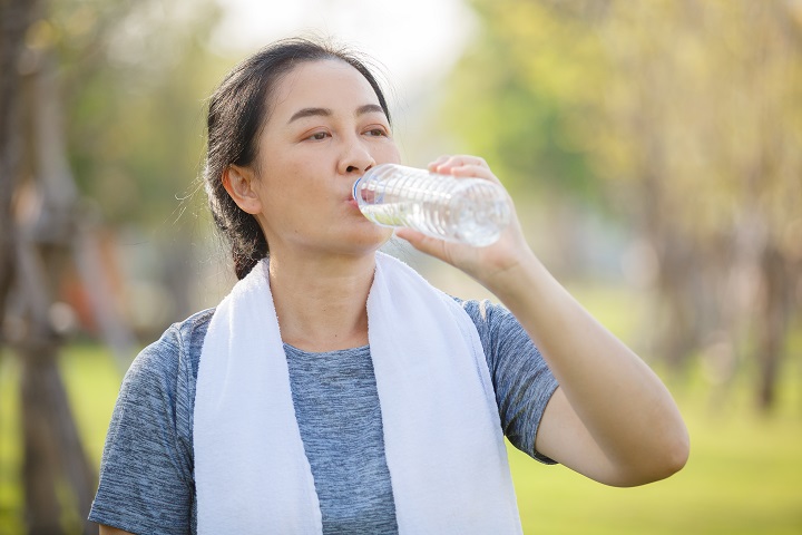 Woman drinking water from a bottle after exercising