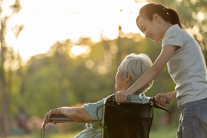 Woman pushing elderly mother on wheelchair after dialysis