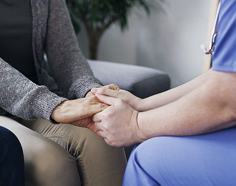 Healthcare worker holding patient's hand as emotional support for dialysis 