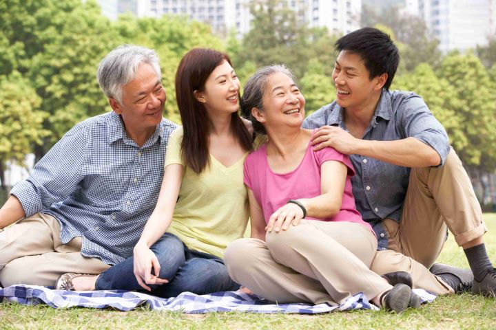 Family happily sitting on open field