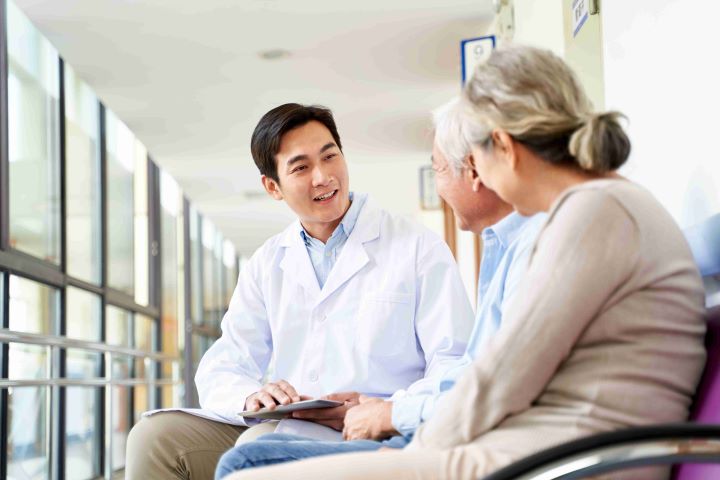 Healthcare work discussing dialysis treatment with elderly couple