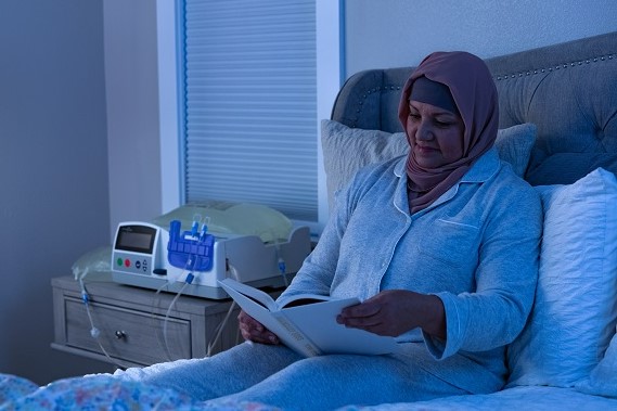 Patient reading while performing Automated Peritoneal Dialysis using a cycler