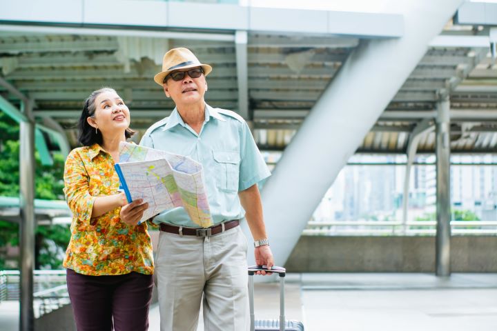Elderly couple holding map and luggage on travelling with dialysis