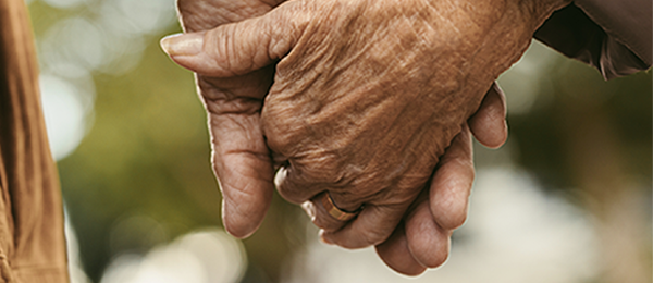 Elderly couple with rings holding hands